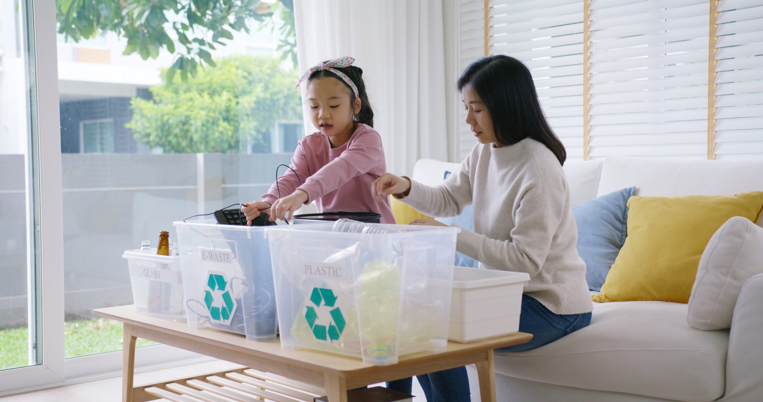 a mother and daughter sort electronic items into recycling bins for safe recycling